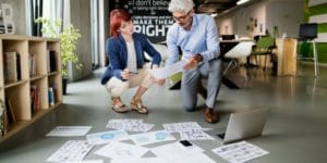Two people kneeling on floor and sorting papers for project