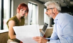man in business suit explaining concept to woman with red hair
