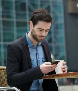 Man sitting outside while sending message on mobile phone