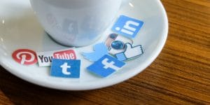 social media stickers on saucer next to coffee cup